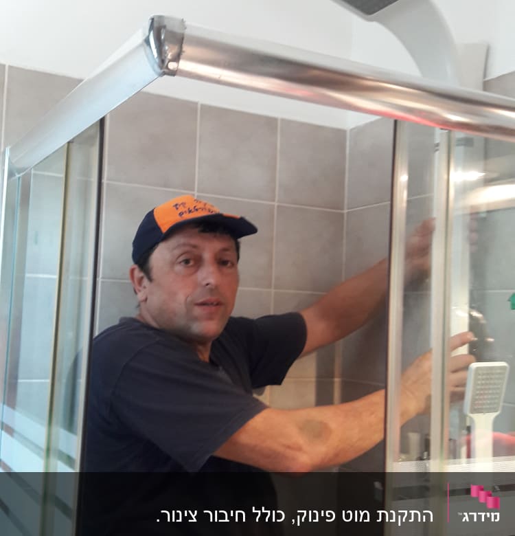 אדם מתקין דלת מקלחת בחדר אמבטיה
